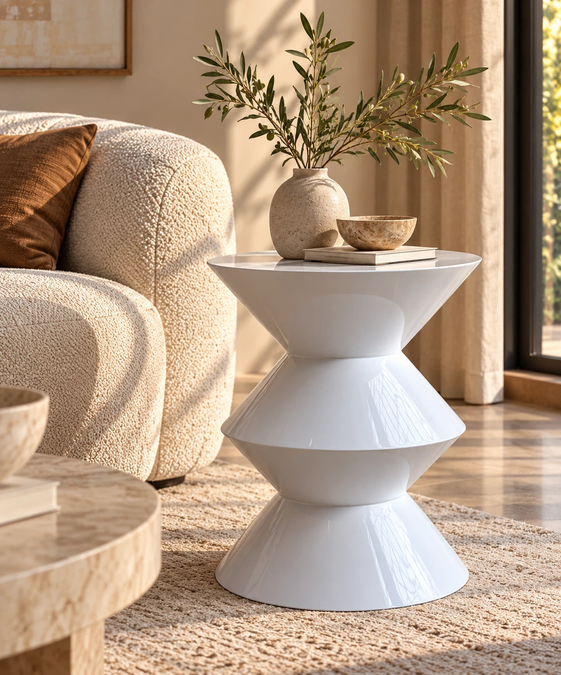 Table d'appoint Cadence blanc brillant près d'un canapé bouclette, avec un vase et une branche d'olivier