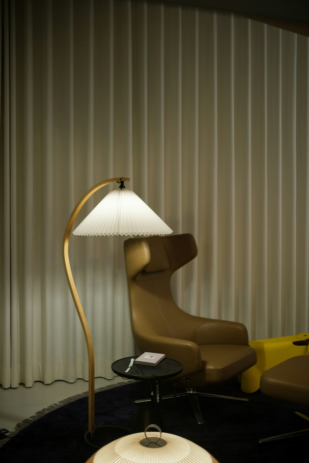Lampadaire en arc à abat-jour plissé près d'un fauteuil